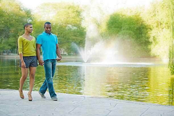 Happy Smiling Couple walking next to a pond. Happy Smiling Couple walking next to a pond and talking. pond fountains stock pictures, royalty-free photos & images