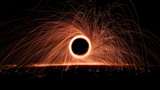 Steel wool fire and sparks at night background. Light art burning steel wool spinning spirals.