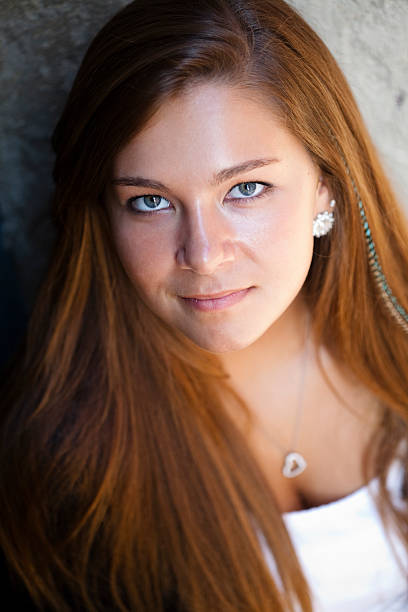 Portrait head and shoulders shot of cute young blond woman in sleeveless top smiling at the camera, studio shot.