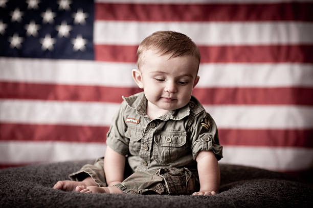istock Pensive Military Baby Child Sitting by American Flag While Thinking 184396973