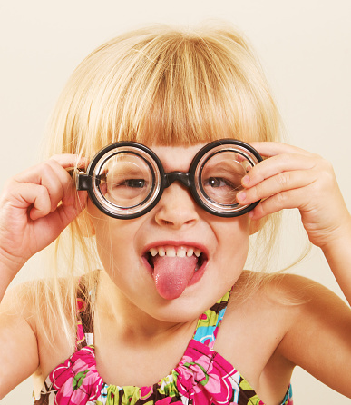 a little nerdy girl in funny glasses making a funny face. 