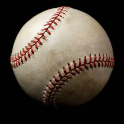 Studio photograph of authentic slightly worn major league style baseball isolated on black.