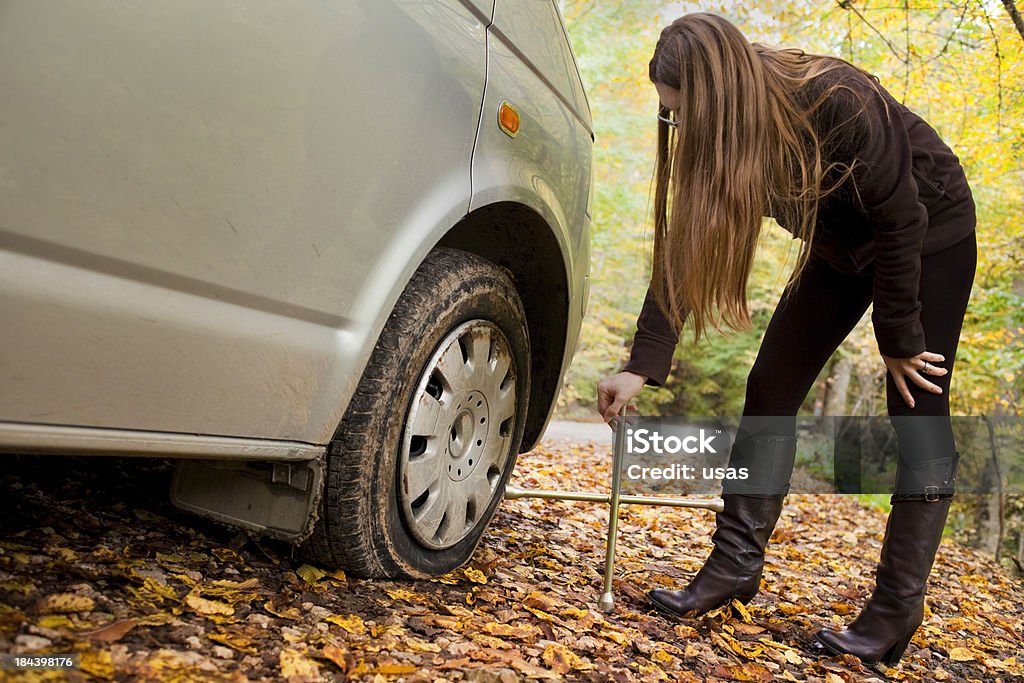 Blown tire and woman Young woman near the flat tire. she is holding a wrench. Autumn Stock Photo