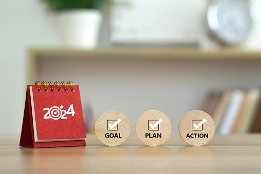 Happy New Year 2024 banner background. 2024 numbers year with target dart icon on red small desk calendar with Goal, Plan, Action on wooden cube. Business goals plan action and success concepts.