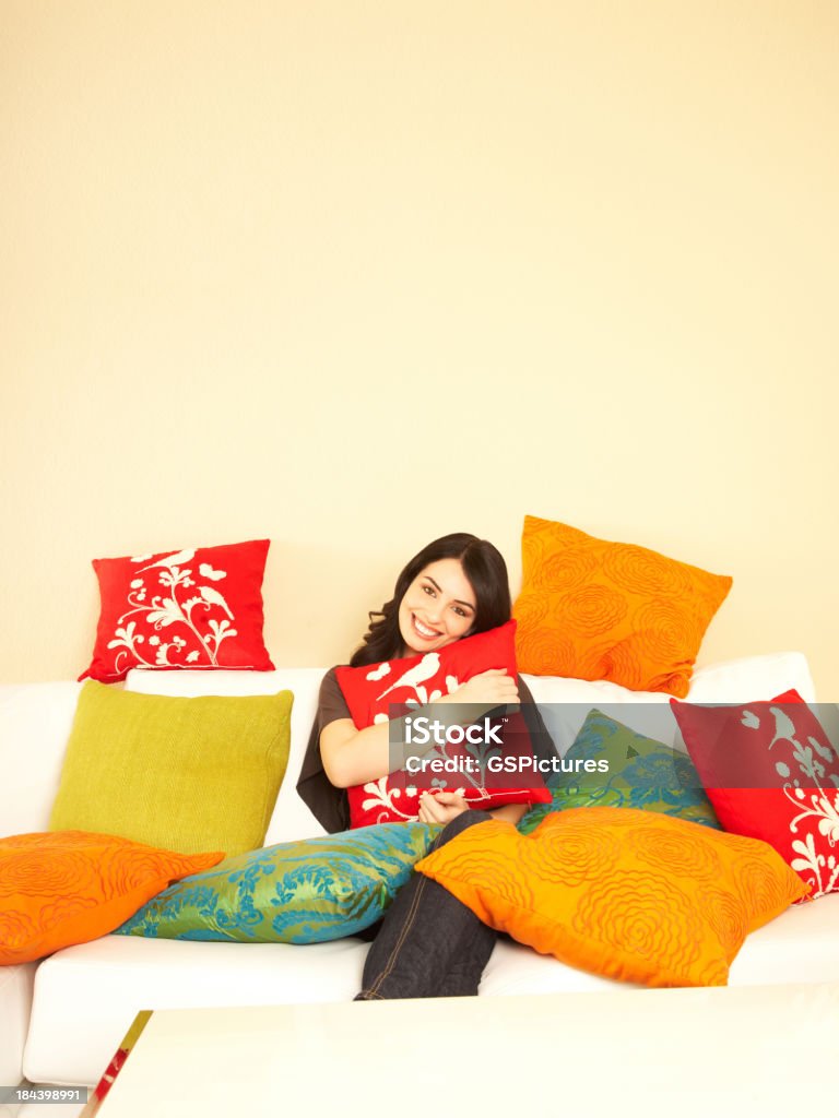 Mulher sorridente em casa no seu sofá rodeada por almofadas - Royalty-free 20-24 Anos Foto de stock