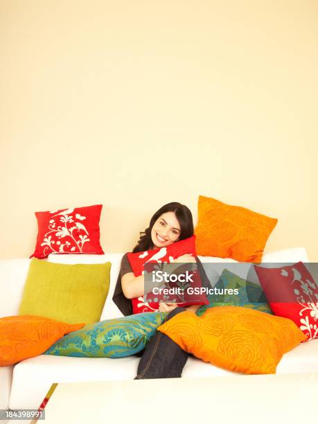 Mulher Sorridente Em Casa No Seu Sofá Rodeada Por Almofadas - Fotografias de stock e mais imagens de 20-24 Anos