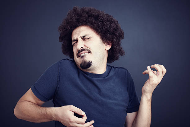 Man with moustache intensely plays air guitar A young man wearing a blue T-shirt with long-puffy black hair, goatee and a mustache plays an imaginary guitar.  There is a dark black and blue background behind him. air guitar stock pictures, royalty-free photos & images