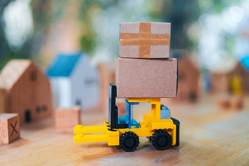 Delivery toy truck with brown package box. Online delivery service concept. A stack of parcels. A delivery vehicle arrives.