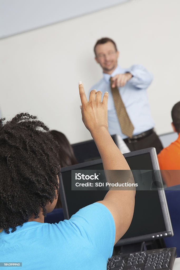 College student raising hand in class College student raising hand in class. Adult Stock Photo