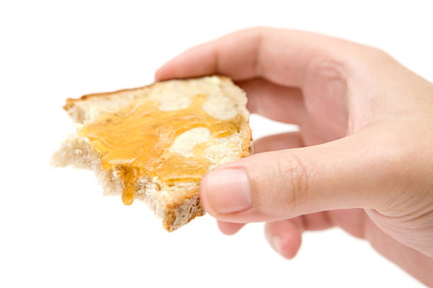 Hand holding a slice of bread with butter and honey. Isolated on a white background.