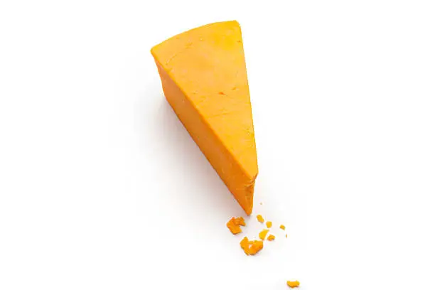 a wedge and some crumbs of cheddar cheese on a white studio background.