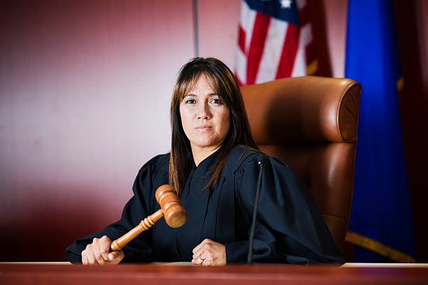 Female judge sitting in court holding her gavel Stock photo of a judge in her fourties sitting on the bench. judge law stock pictures, royalty-free photos & images