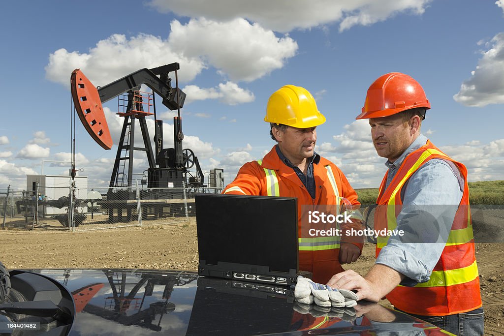 Oil Engineers and Computer An image from the oil industry of two engineers using a computer at a pumpjack. Oil Industry Stock Photo