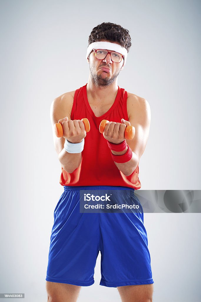 Sad nerdy recreational fitness man exercising with tiny orange weights Portrait of unhappy nerdy sportsman holding light weights 20-29 Years Stock Photo