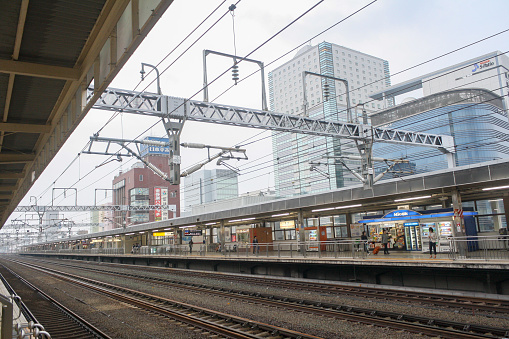 Shizuoka, Japan - May 2014: View of empty shinkansen track and platform in the Shizuoka Station with building and bright sky background. Perspective view.