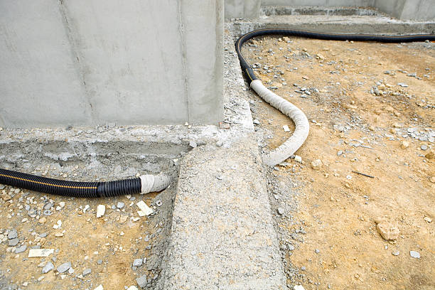House Basement Radon Mitigation System "This image shows the initial pipe component of a sub-slab radon mitigation system. This is an active system which will include a fan to depressurize the area below the basement floor. The drain tile (pipe) will be covered with rock, which will be covered with a membrane and then a concrete slab will be poured. The pipe runs through a concrete footing for a supporting wall and the surrounding walls are poured concrete." easy test stock pictures, royalty-free photos & images