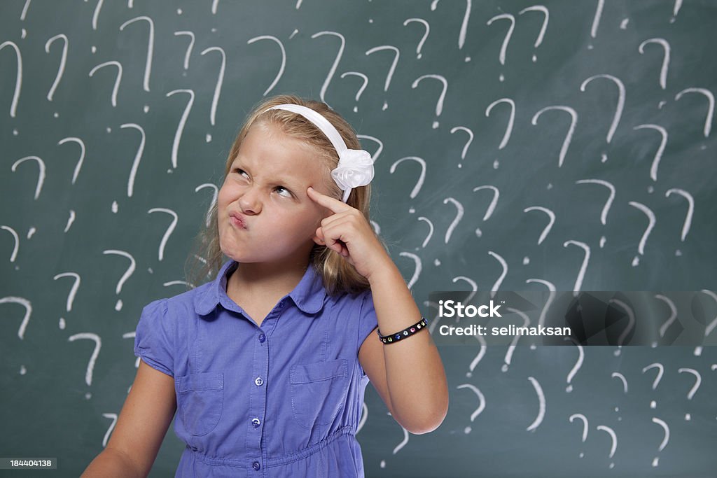 Маленькая девочка с светлыми волосами, думающий перед Классная доска - Стоковые фото Вопросительный знак роялти-фри