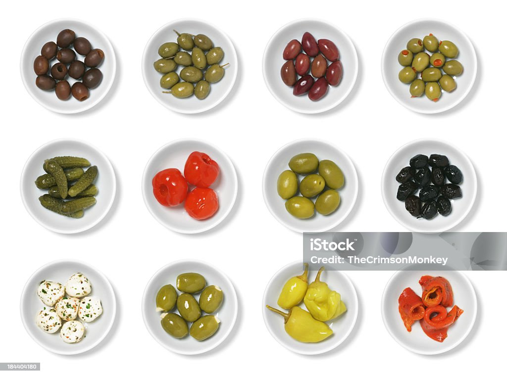 Olives and Antipasto An assortment of olives and antipasto isolated on white.  From left to right, top to bottom, they are: pitted black olives, Greek olives, Kalamata olives, cocktail olives with pimentos, cornichons, sweet pickled red peppers, large green olives, dried olives, marinated mozzarella, feta stuffed olives, pepperoncinis, and roasted red peppers (pimentos). Olive - Fruit Stock Photo
