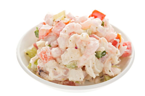 A high angle close up of a small bowl containing some seafood salad intended for a sandwich. Isolated on white.