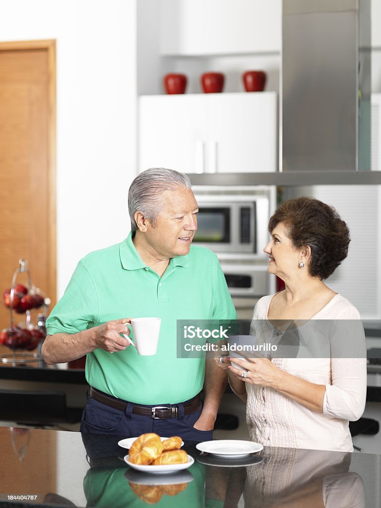 Coppia Senior in cucina mangiare la prima colazione - Foto stock royalty-free di 60-64 anni