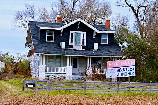 Fairfax, Virginia, USA - December 7, 2023: A run-down house with a “For Sale” sign in front of it in Fairfax County.