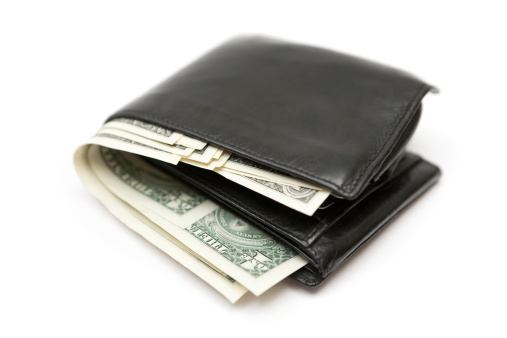 Black leather wallet full of Dollar banknotes. Isolated on a white background.