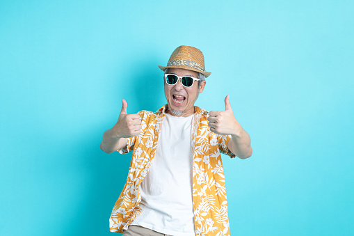 Portrait of Asian energetic senior man posing on blue background with travel clothes. mature man, Asian man. Elderly, Holiday, Travel. studio shot. Multiple emotions.