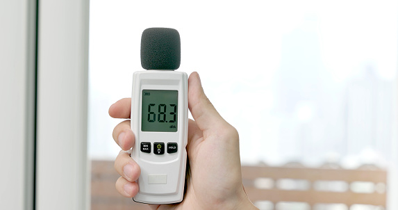 close up hand of asian male home inspector is using sound level meter to check the interior noise degree