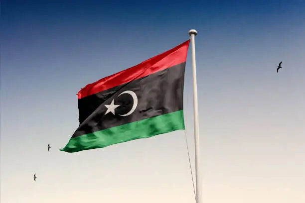 Photo of Libya flag fluttering in the wind on sky.
