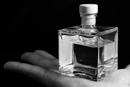 Bottle of perfume on hand with black background - black and white