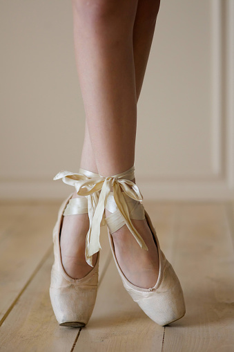 Female ballet dancer legs in white Pointe shoes. The concept of culture and art.