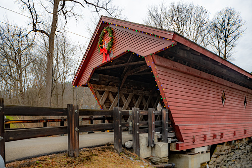 Historic timber one lane covered bridge in the Town of Newfield, Tompkins County NY with holiday lights.