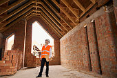 Construction superintendent inspecting timber roof trusses from inside building