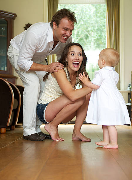Happy parents helping baby take first steps