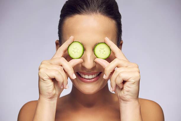 kobieta gospodarstwa plasterki ogórka na oczy - cucumber human eye spa treatment health spa zdjęcia i obrazy z banku zdjęć