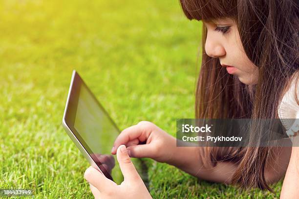 Mała Dziewczynka Leżąc Na Trawie I Dotyka Ekranu Tabletka - zdjęcia stockowe i więcej obrazów Dziecko