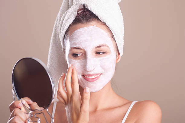 istock girl applying  mask on  face and looking in the mirror 184434562