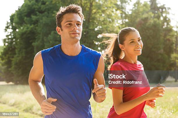 Young Couple Jogging Together Outdoors In Sunshine Stock Photo - Download Image Now - Couple - Relationship, Jogging, Running