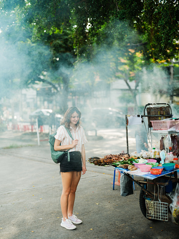 Woman buying street food BBQ in Bangkok during her vacation