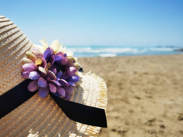 straw hat with a flower on a beach stock photo