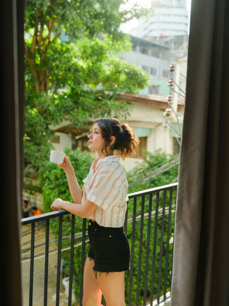 istock Woman drinking coffee  on the balcony in summer with trees visible from the window 1844470257