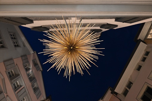 A stunning illuminated sunburst hanging from a building against a starry night sky, creating an awe-inspiring atmosphere