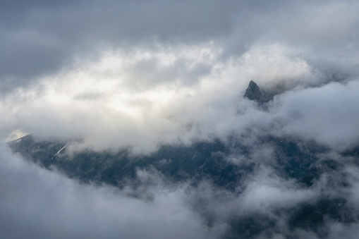 Gloomy mountains. Sharp single peak among the clouds. Mysterious mountain near Western Sayans.