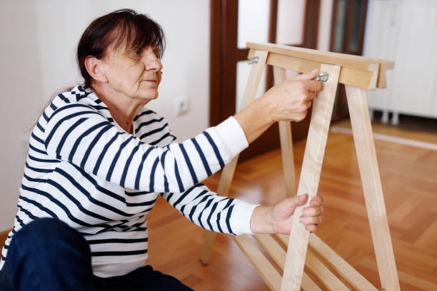 uma mulher sênior montando móveis em seu novo apartamento - screw sitting on floor building activity working - fotografias e filmes do acervo