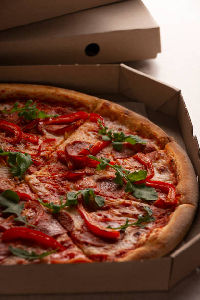 istock Large Pizza in open carton box on kitchen table closeup view 1844512167