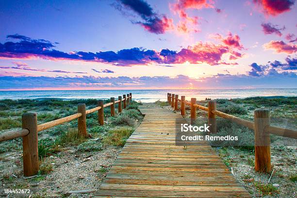 Wooden Walkway Through Grass To Beach Under Colorful Sky Stock Photo - Download Image Now