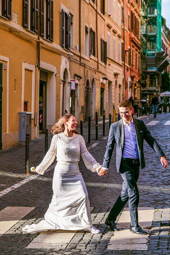 Rome, Italy, November 11 -- A happy couple walks along an alley in the Rione Monti(Monti district) formerly called the Suburra district, in the heart of the historic center of Rome. The Monti district is a trendy and multi-ethnic quarter much loved by the younger generations and tourists for the presence of trendy pubs, fashion shops and restaurants, where you can find the true soul of the Eternal City. The Rione Monti, located between Via Nazionale and the Fori Imperiali, is also rich in numerous churches in Baroque style and archaeological remains. In 1980 the historic center of Rome was declared a World Heritage Site by Unesco. Image in high definition quality.