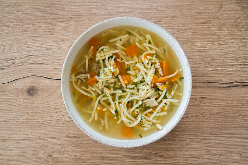 Simple traditional chicken noodle soup with carrots and parsley, ready to eat, european food, top view