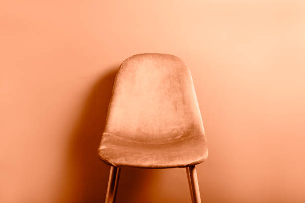 Modern Velour Chair peach color, color trend 2024 on wooden legs, grey background