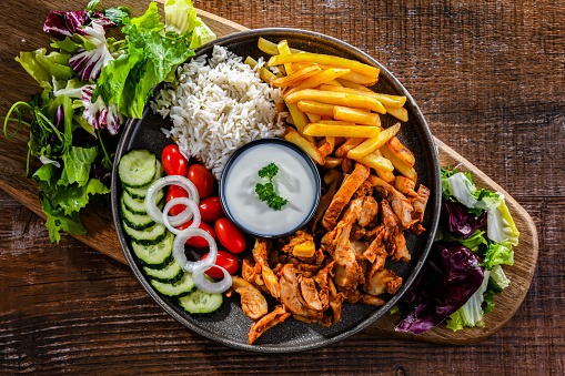 Kebab served with rice, french fries, pitta bread, vegetables and tzatziki
